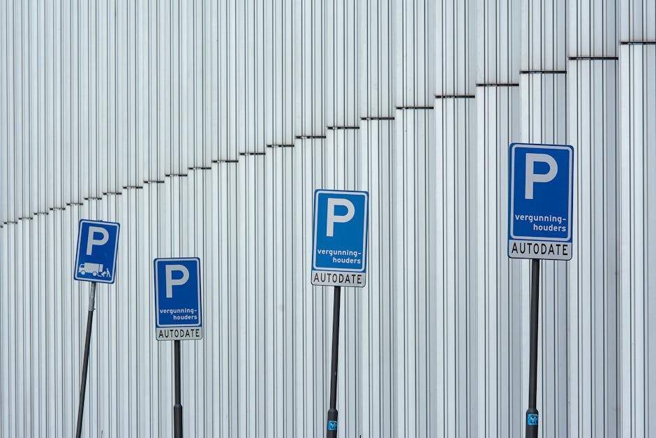 Four blue parking restriction signs mounted on black metal poles are positioned against a vertically ridged metallic wall. The signs display a prominent white 'P' and include additional text about parking permits, with the smaller text reading 'vergunninghouders' and 'AUTODATE.' The signs are aligned at varying heights and angles, with the second sign from the left slightly tilted. The lighting is natural, creating subtle shadows on the metallic background. This scene reflects parking regulations relevant to house removals and moving logistics, which are important considerations covered in the context of applying for parking suspension permits in Pinner, as detailed on manwithvanpinner.co.uk.
